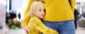 photo of a blond child in a yellow shirt hugging their grownup, also wearing a yellow shirt. The child looks anxious and like they don't want to let go of their grown up.